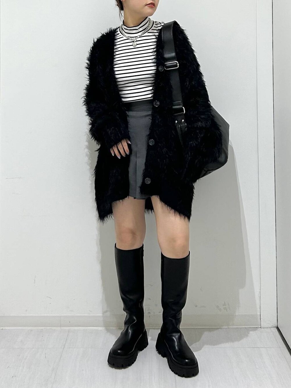 ブラック系のカーディガン/ボレロ、ブラック系のブーツ、ブラック系のショルダーバッグを着用したレディースの秋コーディネートの2枚目の写真