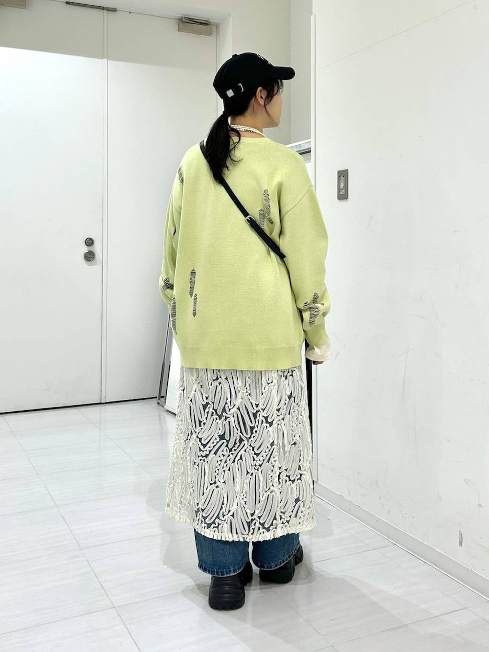 ブルー系のデニムパンツ、ホワイト系のワンピース、イエロー系のニット/セーターを着用したレディースの冬コーディネートの5枚目の写真