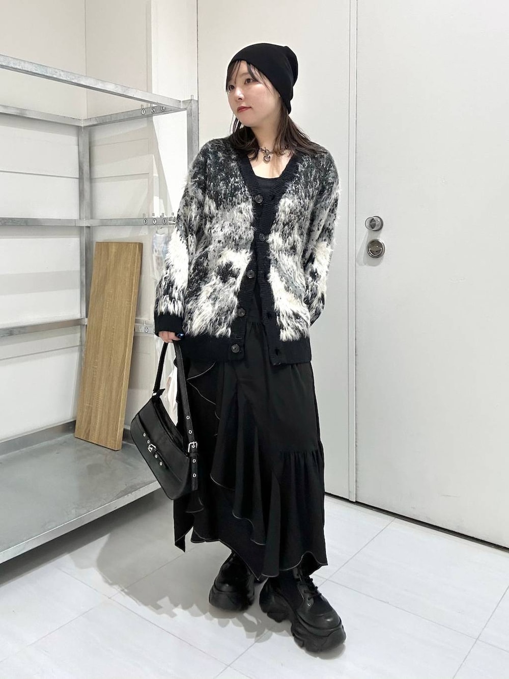 ブラック系のブーツ、ブラック系のカーディガン/ボレロ、ブラック系のスカートを着用したレディースの冬コーディネートの2枚目の写真