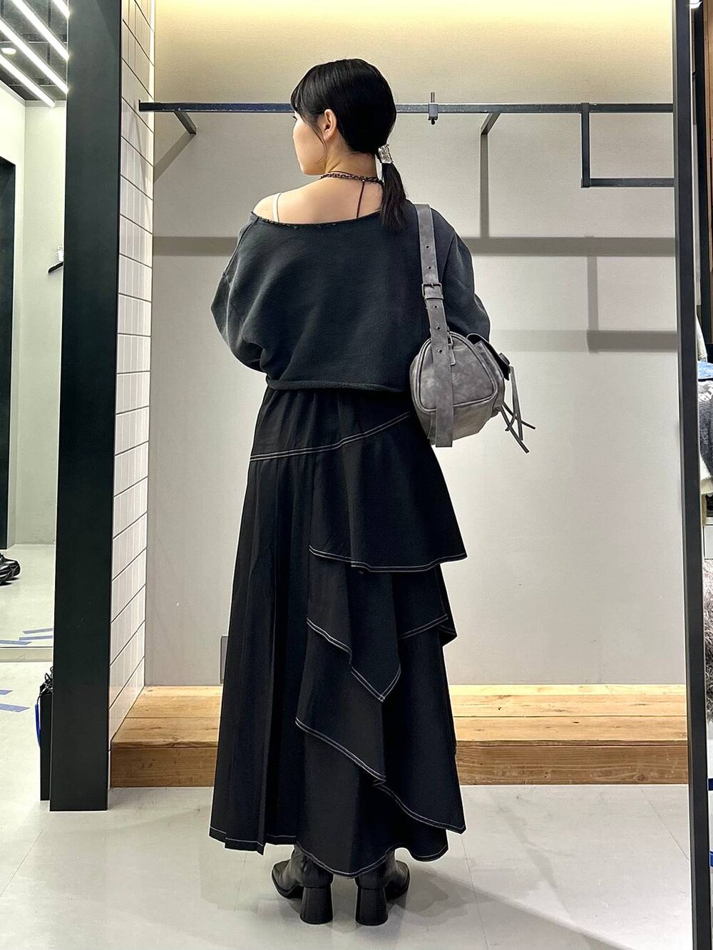 ブラック系のブーツ、ブラック系のスカート、グレー系のスウェットを着用したレディースの秋コーディネートの3枚目の写真