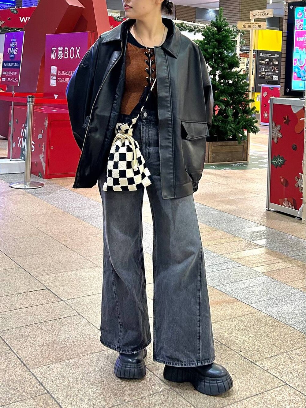 ブラック系のデニムパンツ、ブラック系のブルゾン、ブラック系のブーツを着用したレディースの秋コーディネートの3枚目の写真