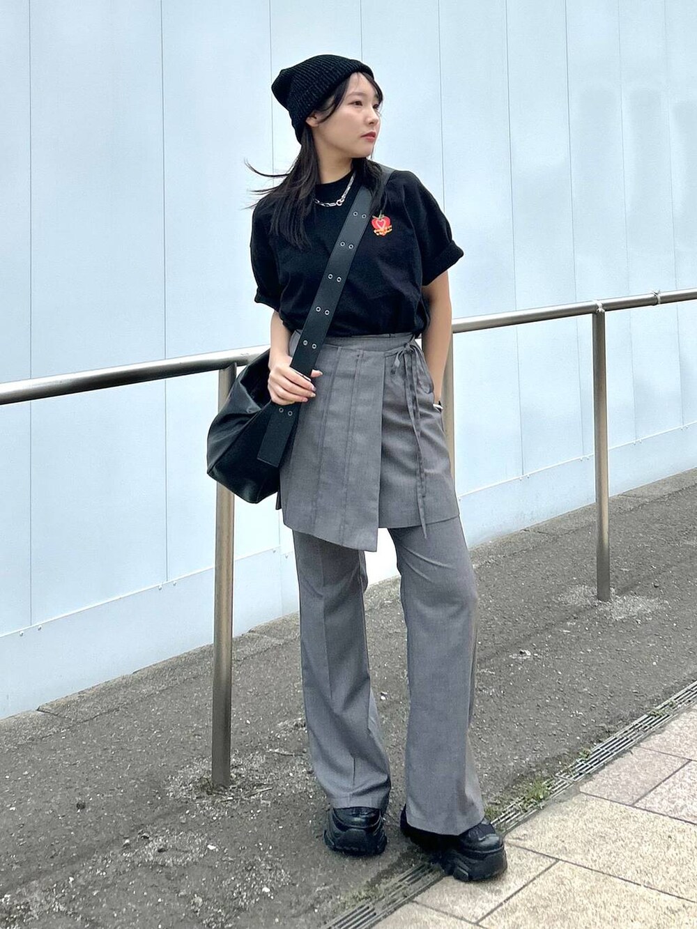 ブラック系のショルダーバッグ、グレー系のスカート、グレー系のスラックスを着用したレディースの春コーディネートの2枚目の写真