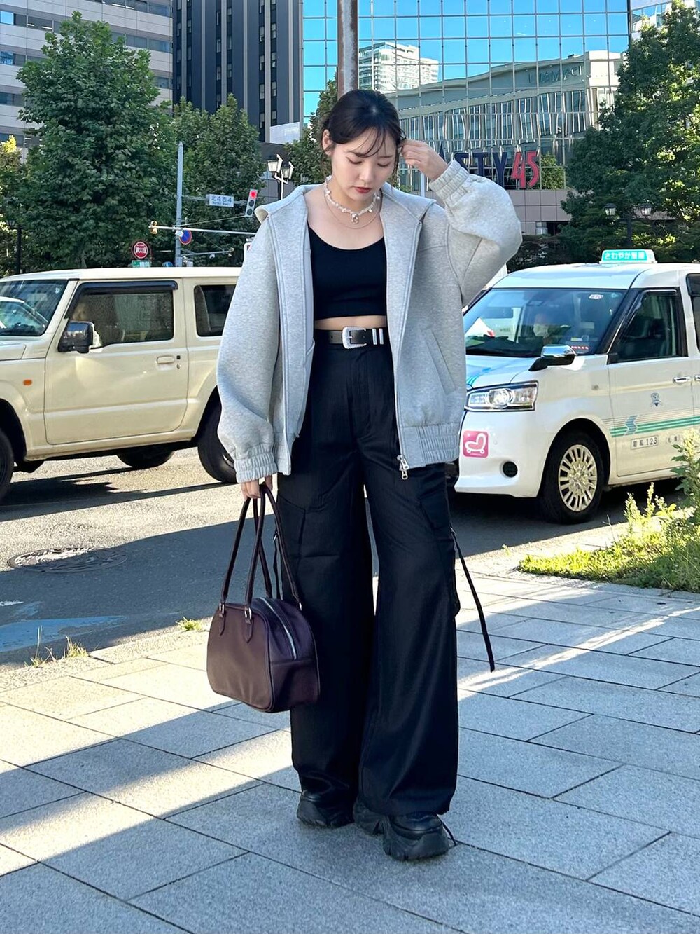 グレー系のパーカー、レッド系のボストンバッグ、ブラック系のスラックスを着用したレディースの秋コーディネートの3枚目の写真