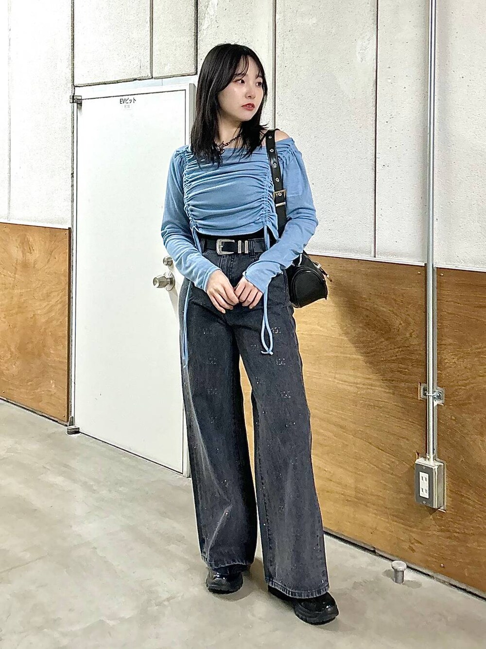 ブラック系のデニムパンツ、ブラック系のスニーカー、ブラック系のショルダーバッグを着用したレディースの春コーディネートの3枚目の写真