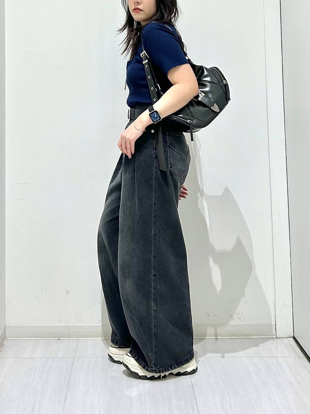 ブラック系のデニムパンツ、ブルー系のニット/セーター、ブラック系のベルトを着用したレディースの春コーディネートの5枚目の写真