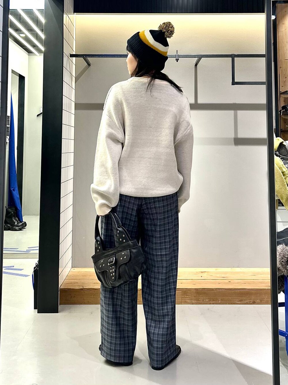 ブラック系のブーツ、グレー系のスラックス、ブラック系のハンドバッグを着用したレディースの秋コーディネートの3枚目の写真