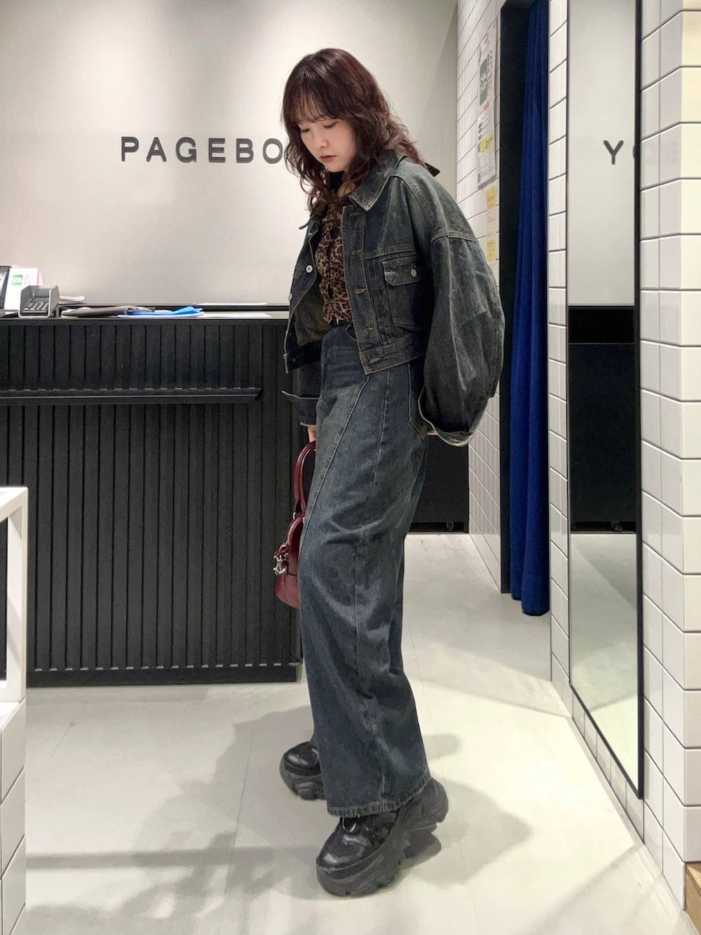 ブルー系のデニムパンツ、ブラック系のスニーカー、ブルー系のデニムジャケットを着用したレディースの秋コーディネートの4枚目の写真