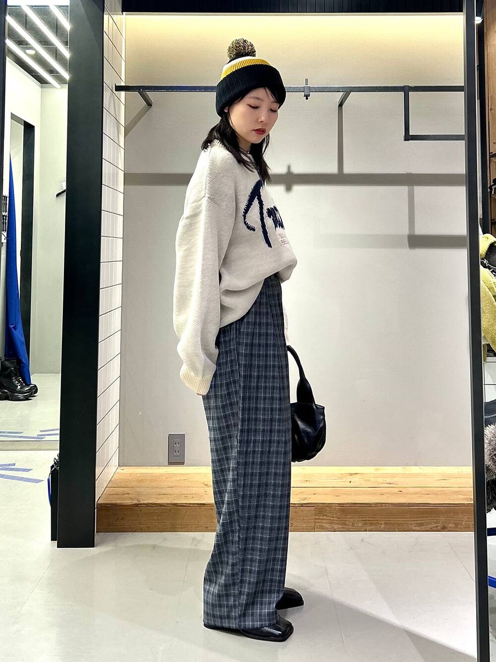 ブラック系のブーツ、グレー系のスラックス、ブラック系のハンドバッグを着用したレディースの秋コーディネートの2枚目の写真