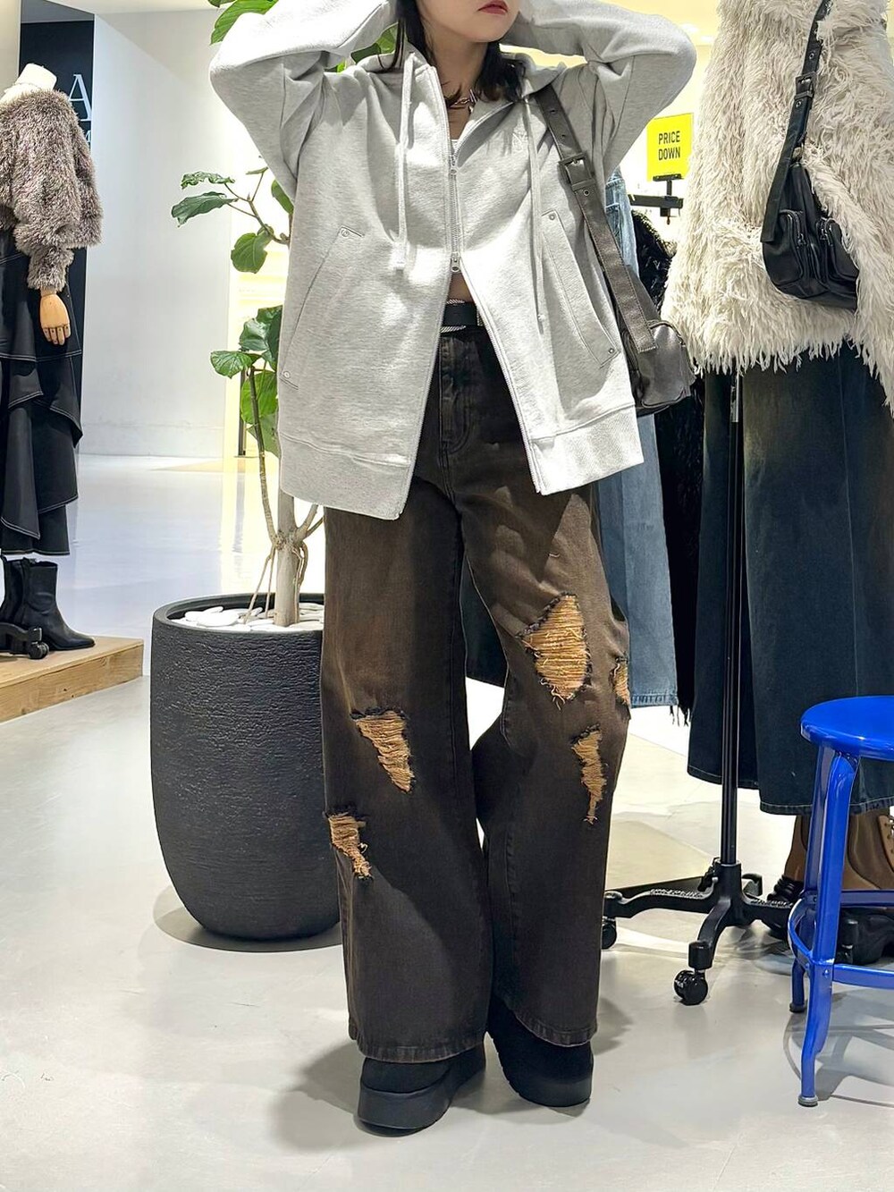 ブラック系のショルダーバッグ、グレー系のパーカー、ブラック系のブーツを着用したレディースの冬コーディネートの3枚目の写真