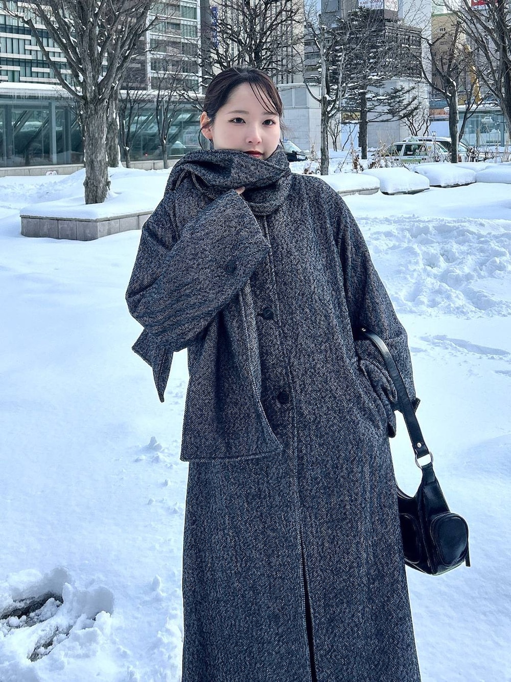 ブラック系のチェスターコート、ブラック系のスラックス、ブラック系のショルダーバッグを着用したレディースの冬コーディネートの3枚目の写真