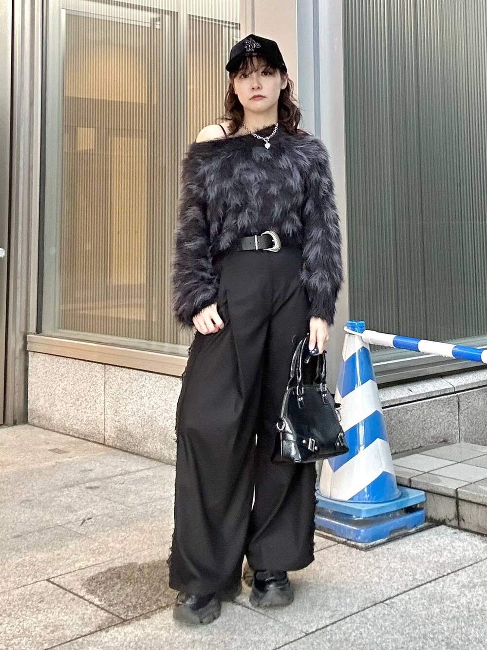 ブラック系のニット/セーター、ブラック系のスニーカー、ブラック系のショルダーバッグを着用したレディースの秋コーディネートの4枚目の写真