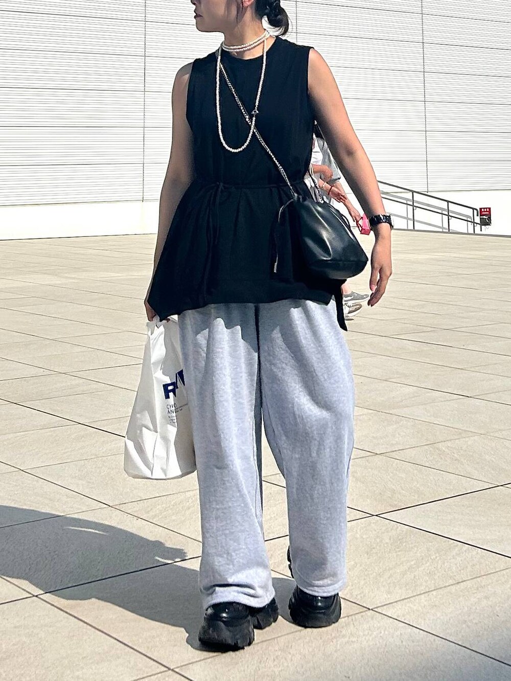 ブラック系のスニーカー、グレー系のスウェットパンツ、ブラック系のTシャツ/カットソーを着用したレディースの夏コーディネートの2枚目の写真