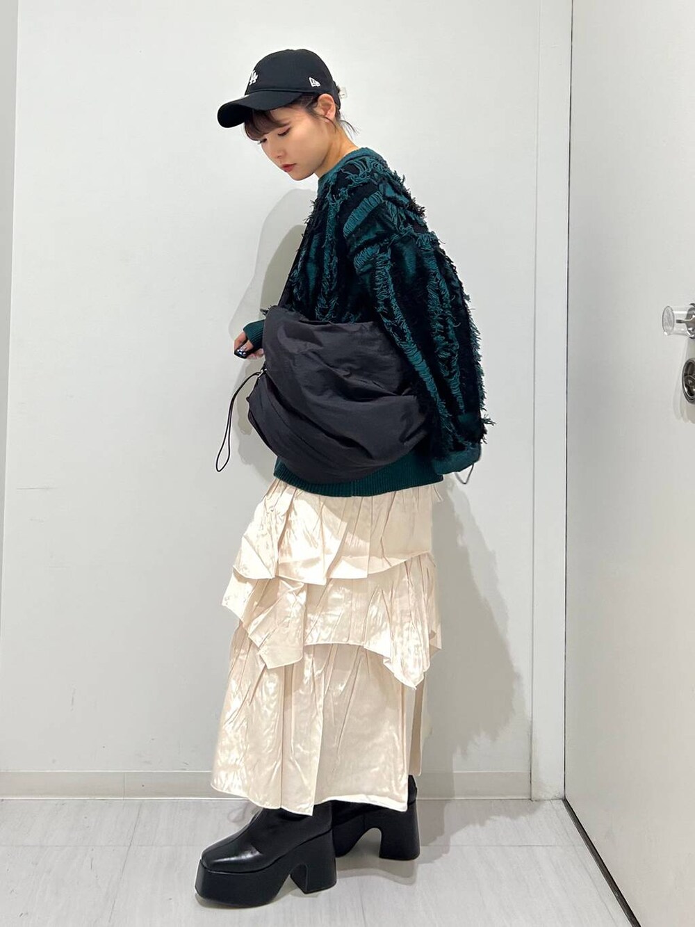 ベージュ系のスカート、ブラック系のブーツ、ブラック系のショルダーバッグを着用したレディースの秋コーディネートの4枚目の写真