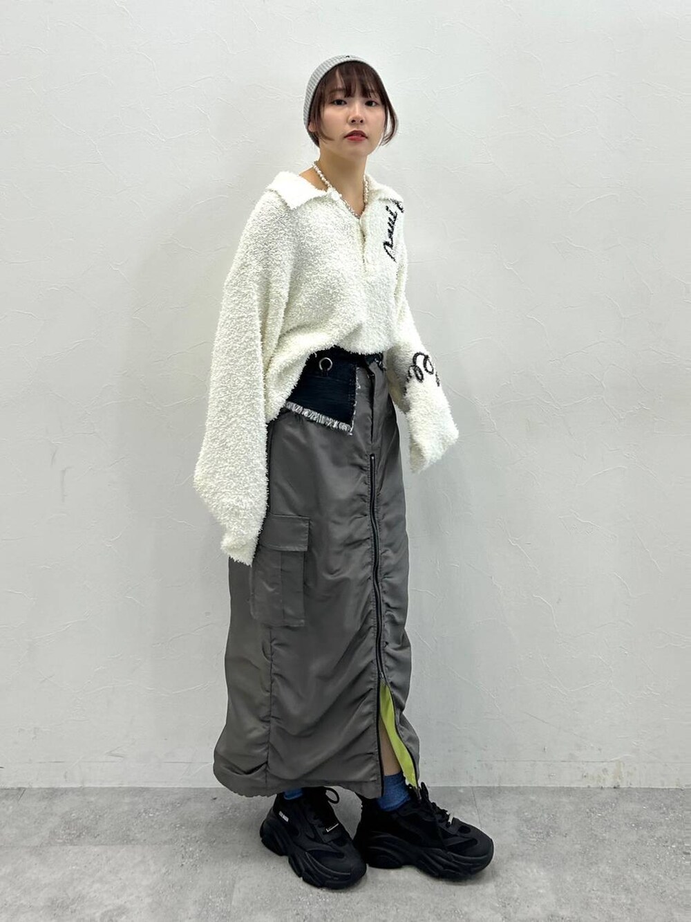 グレー系のスカート、ホワイト系のニット/セーターを着用したレディースの冬コーディネートの2枚目の写真