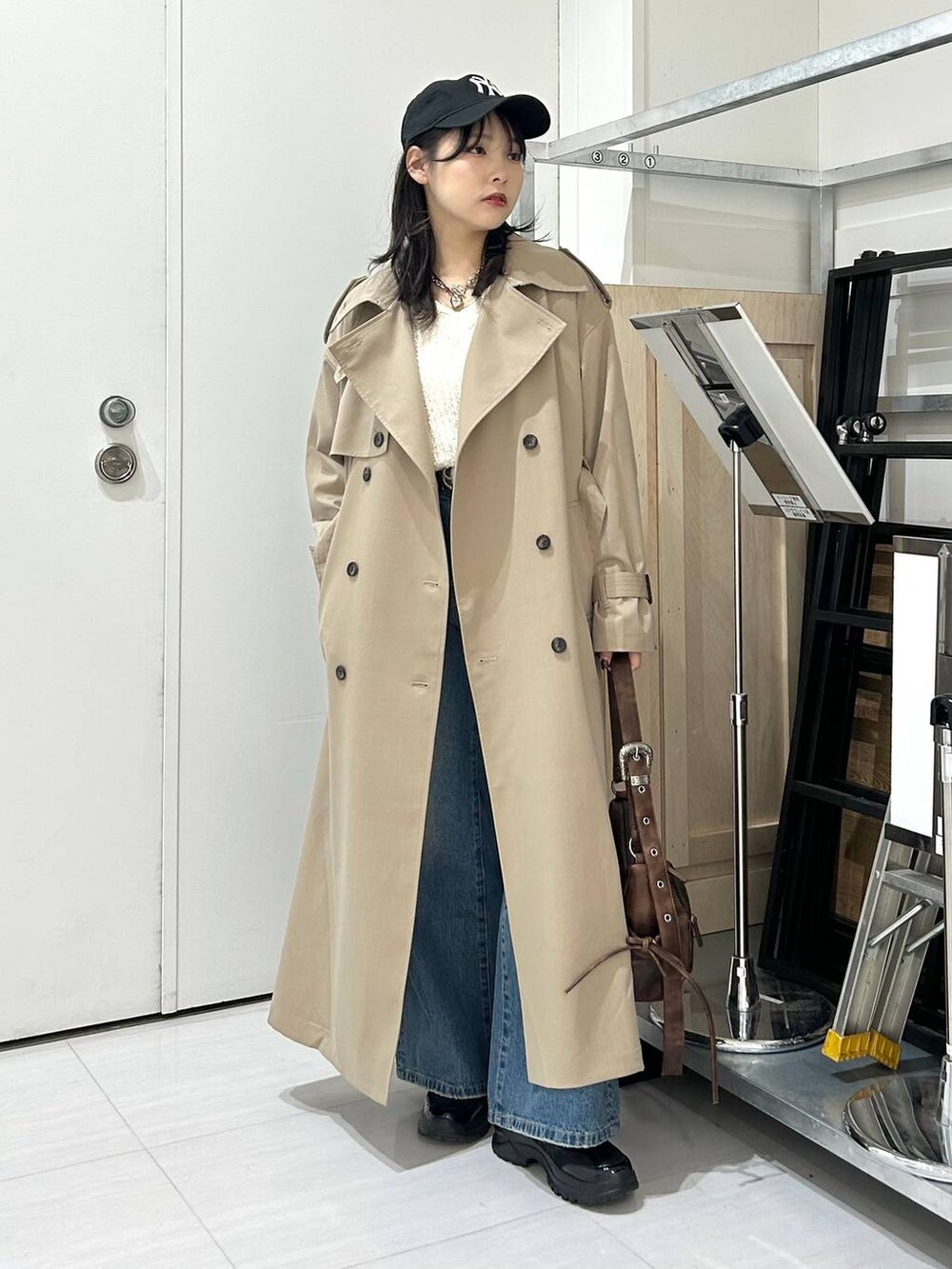 ブルー系のデニムパンツ、ブラウン系のショルダーバッグ、ベージュ系のトレンチコートを着用したレディースの冬コーディネートの4枚目の写真