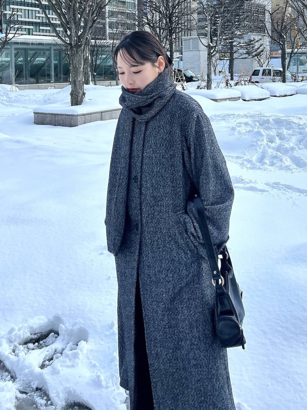 ブラック系のチェスターコート、ブラック系のスラックス、ブラック系のショルダーバッグを着用したレディースの冬コーディネートの2枚目の写真