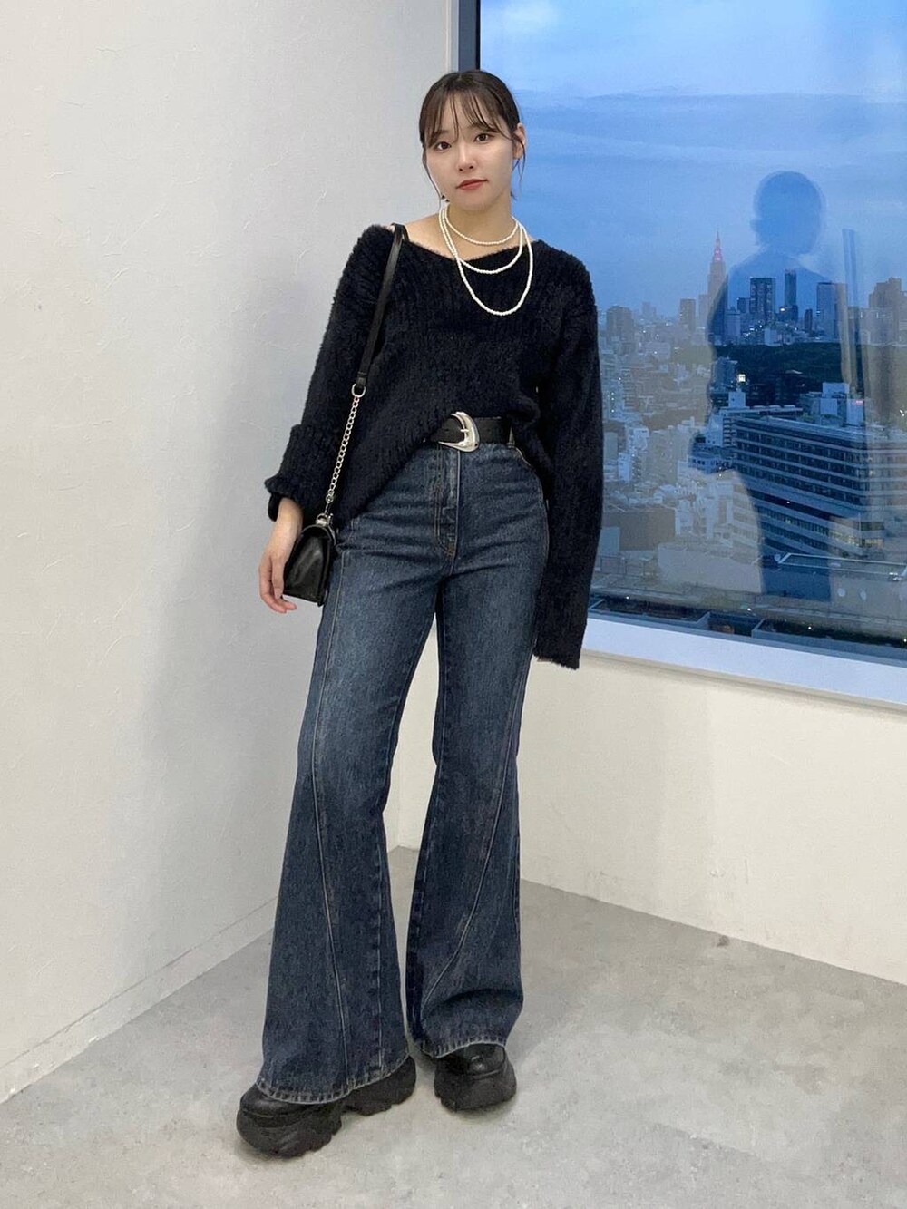 ブラック系のスニーカー、ブルー系のデニムパンツ、ブラック系のニット/セーターを着用したレディースの秋コーディネートの7枚目の写真