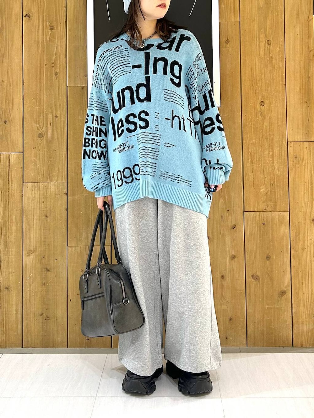 ブラック系のスニーカー、グレー系のボストンバッグ、ブルー系のニット/セーターを着用したレディースの冬コーディネートの3枚目の写真