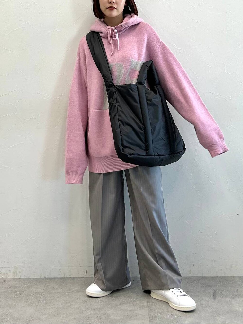 グレー系のスラックス、ブラック系のトートバッグ、ピンク系のニット/セーターを着用したレディースの冬コーディネートの4枚目の写真