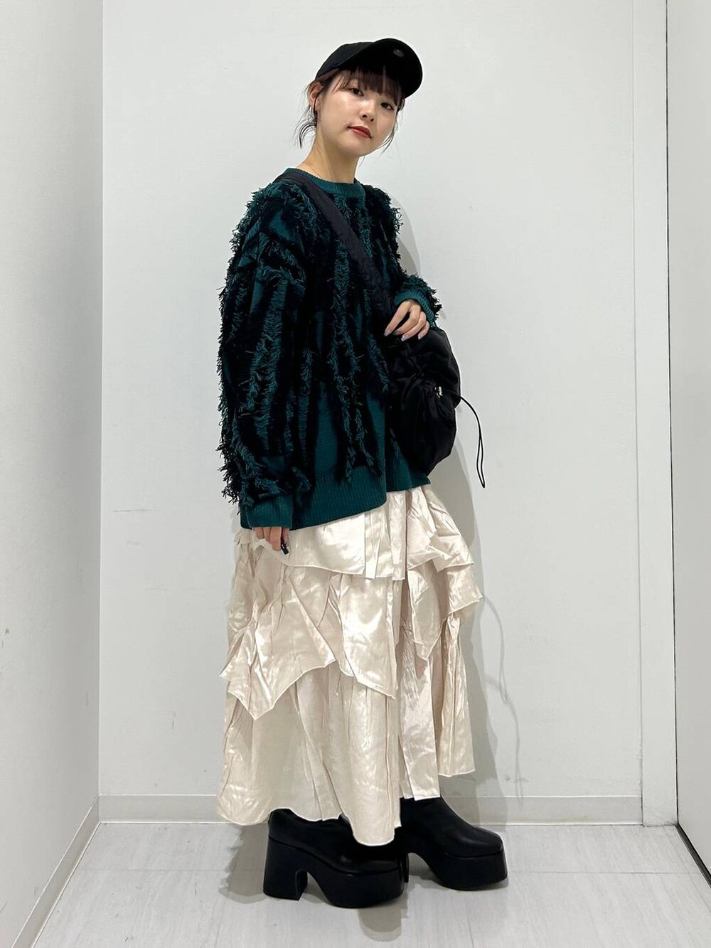 ベージュ系のスカート、ブラック系のブーツ、ブラック系のショルダーバッグを着用したレディースの秋コーディネートの3枚目の写真