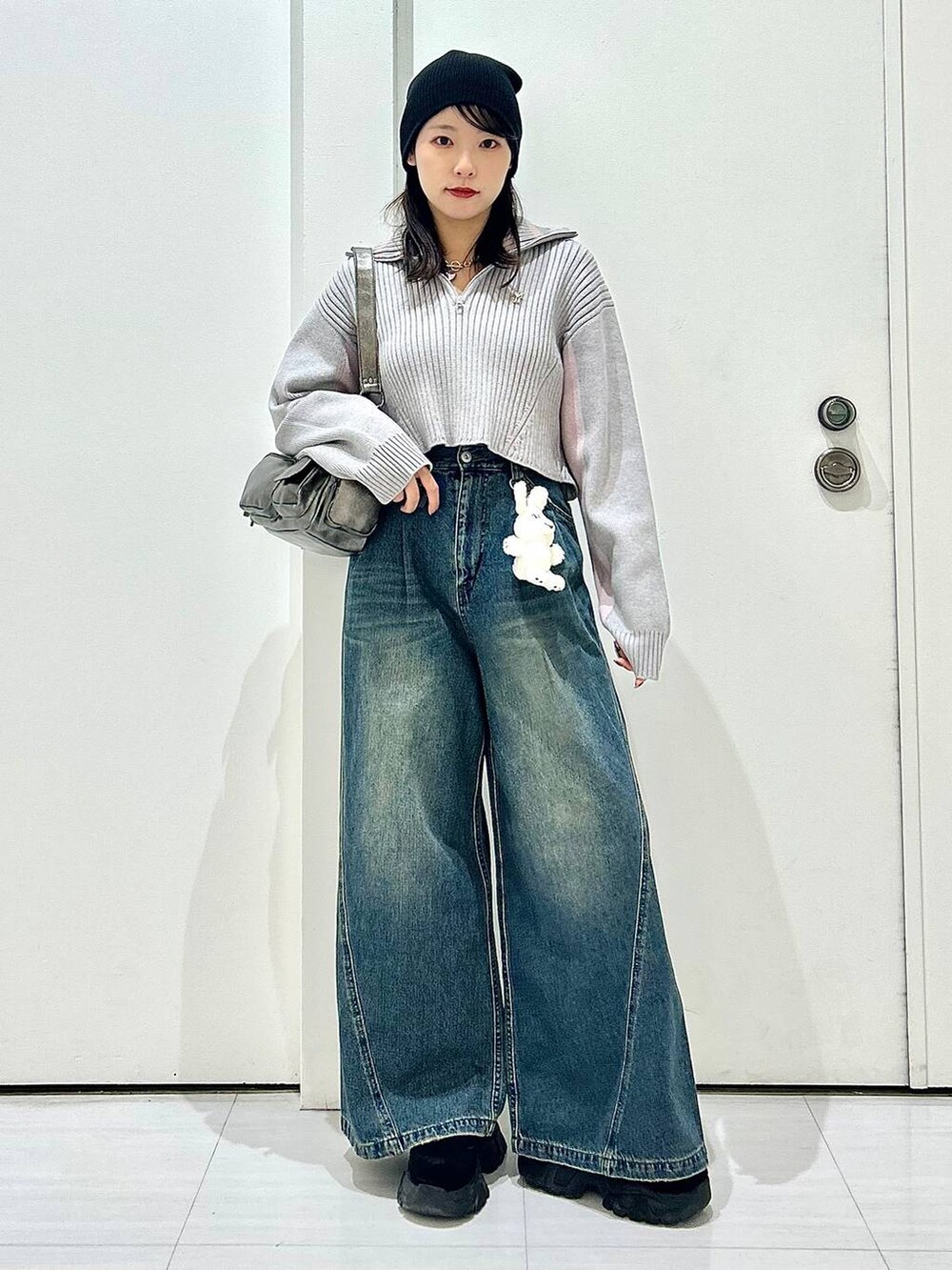 ブルー系のデニムパンツ、グレー系のショルダーバッグ、グレー系のニット/セーターを着用したレディースの秋コーディネートの2枚目の写真