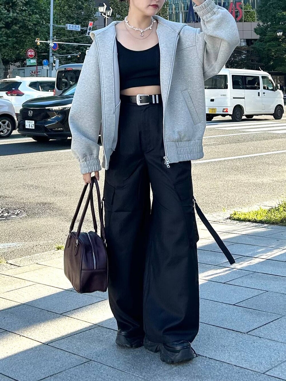 グレー系のパーカー、レッド系のボストンバッグ、ブラック系のスラックスを着用したレディースの秋コーディネートの10枚目の写真