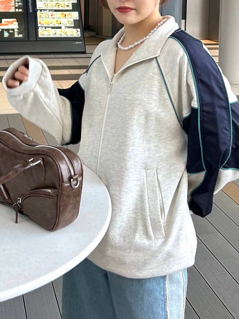 ブルー系のデニムパンツ、ブラウン系のボストンバッグ、ベージュ系のスウェットを着用したレディースの冬コーディネートの3枚目の写真