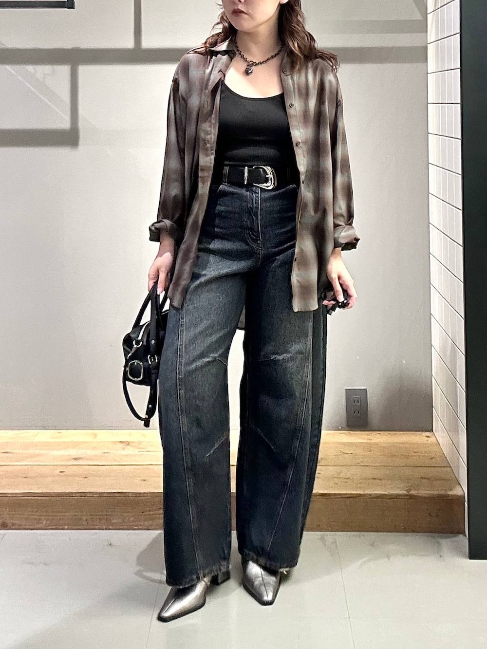 ブラック系のシャツ/ブラウス、ブルー系のデニムパンツ、ブラック系のショルダーバッグを着用したレディースの秋コーディネートの3枚目の写真