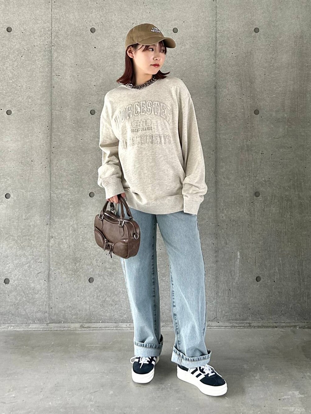 ベージュ系のスウェット、ブルー系のデニムパンツ、ブラック系のスニーカーを着用したレディースの春コーディネートの2枚目の写真