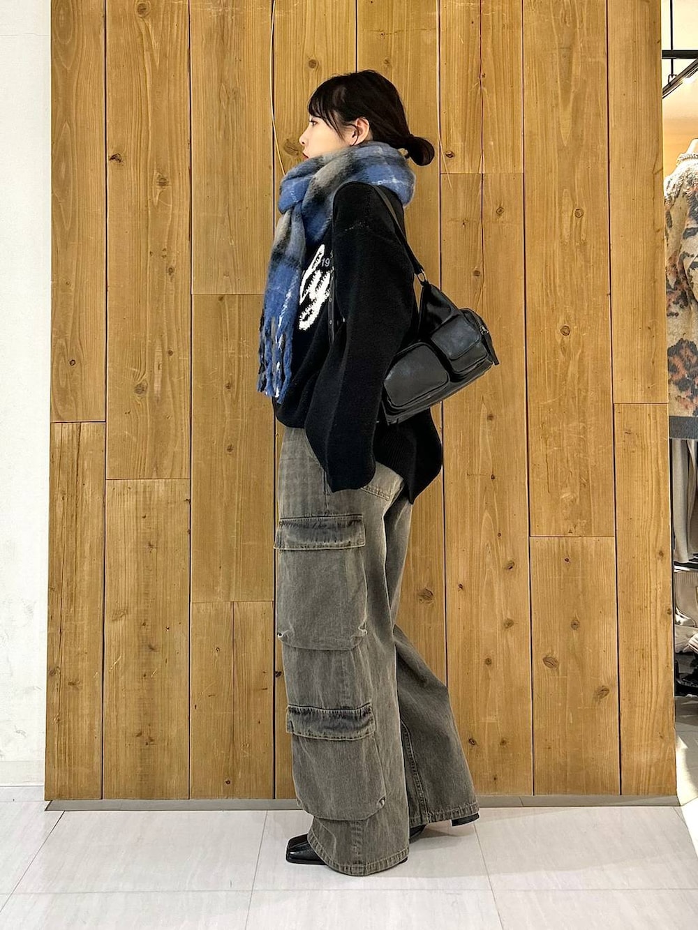 ブラック系のショルダーバッグ、ブラック系のニット/セーター、ブラック系のデニムパンツを着用したレディースの冬コーディネートの3枚目の写真