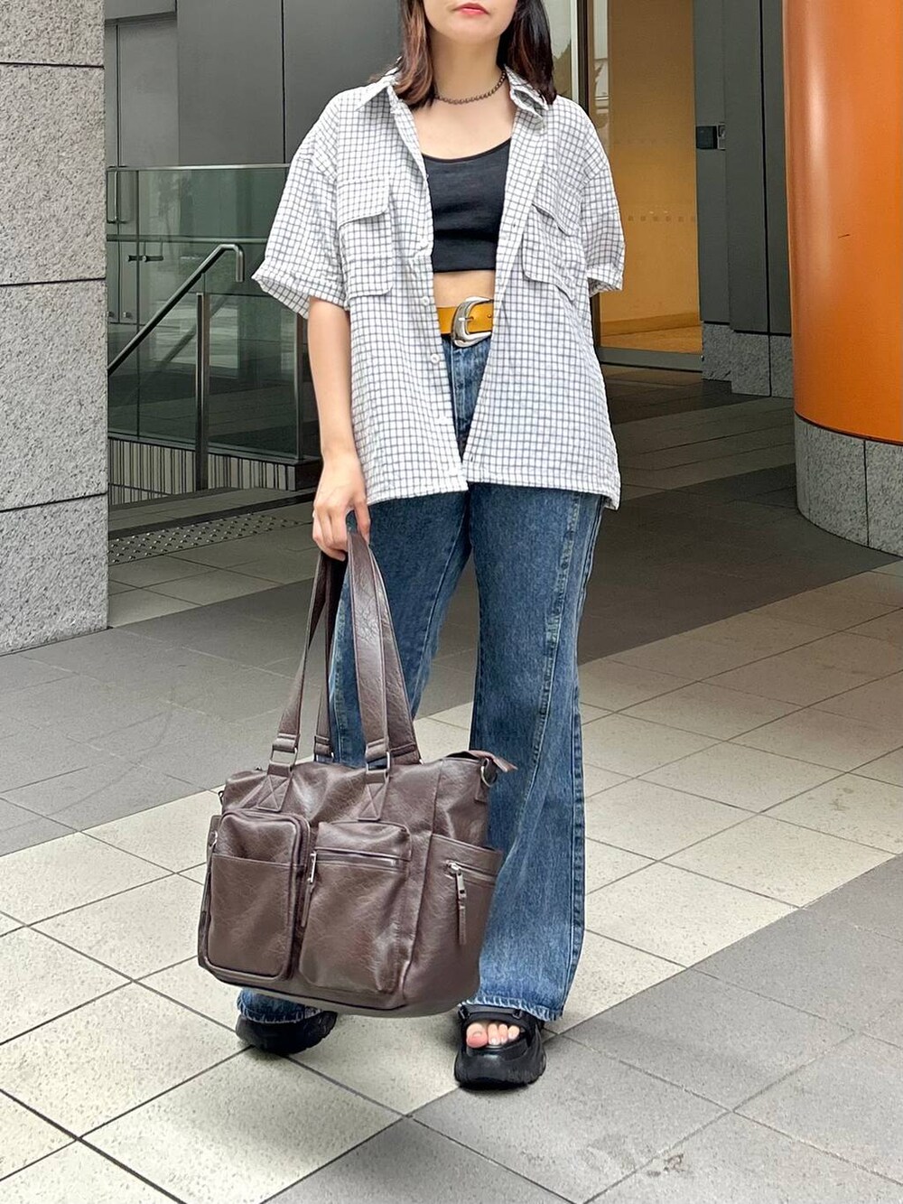 ブルー系のデニムパンツ、ホワイト系のシャツ/ブラウス、ブラック系のボストンバッグを着用したレディースの夏コーディネートの3枚目の写真