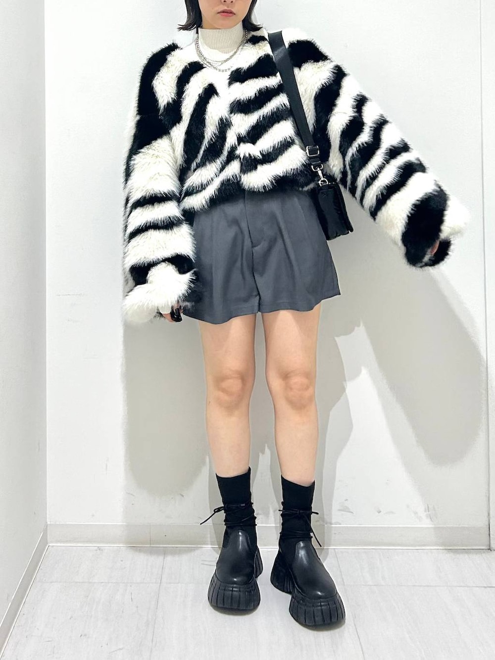 ホワイト系のニット/セーター、ブラック系のショルダーバッグ、ホワイト系のブルゾンを着用したレディースの秋コーディネートの2枚目の写真