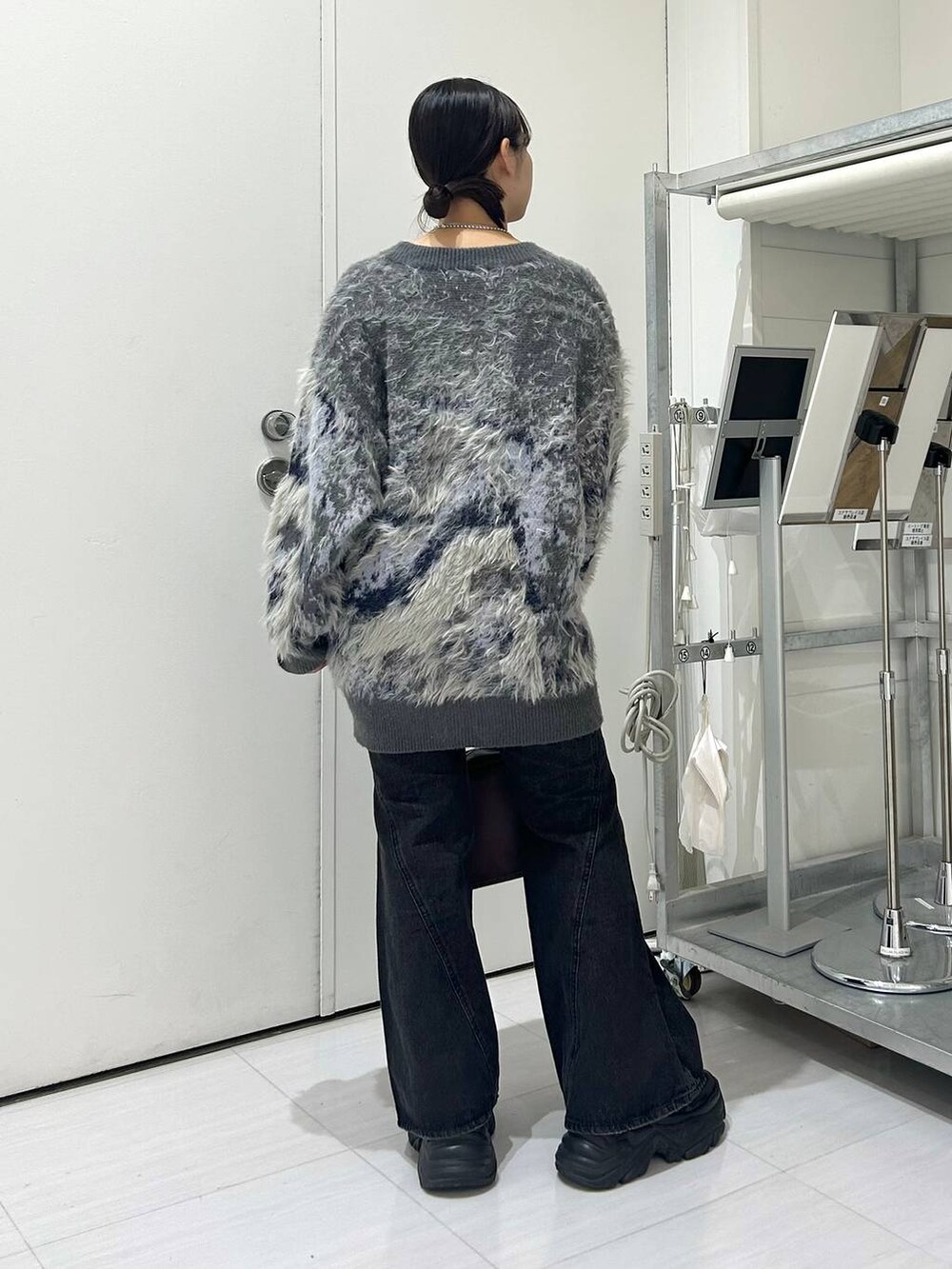 ブラック系のスニーカー、ブルー系のデニムパンツ、レッド系のボストンバッグを着用したレディースの秋コーディネートの5枚目の写真