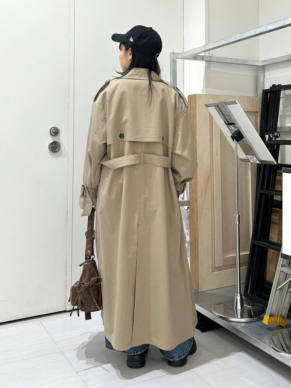 ブルー系のデニムパンツ、ブラウン系のショルダーバッグ、ベージュ系のトレンチコートを着用したレディースの冬コーディネートの6枚目の写真