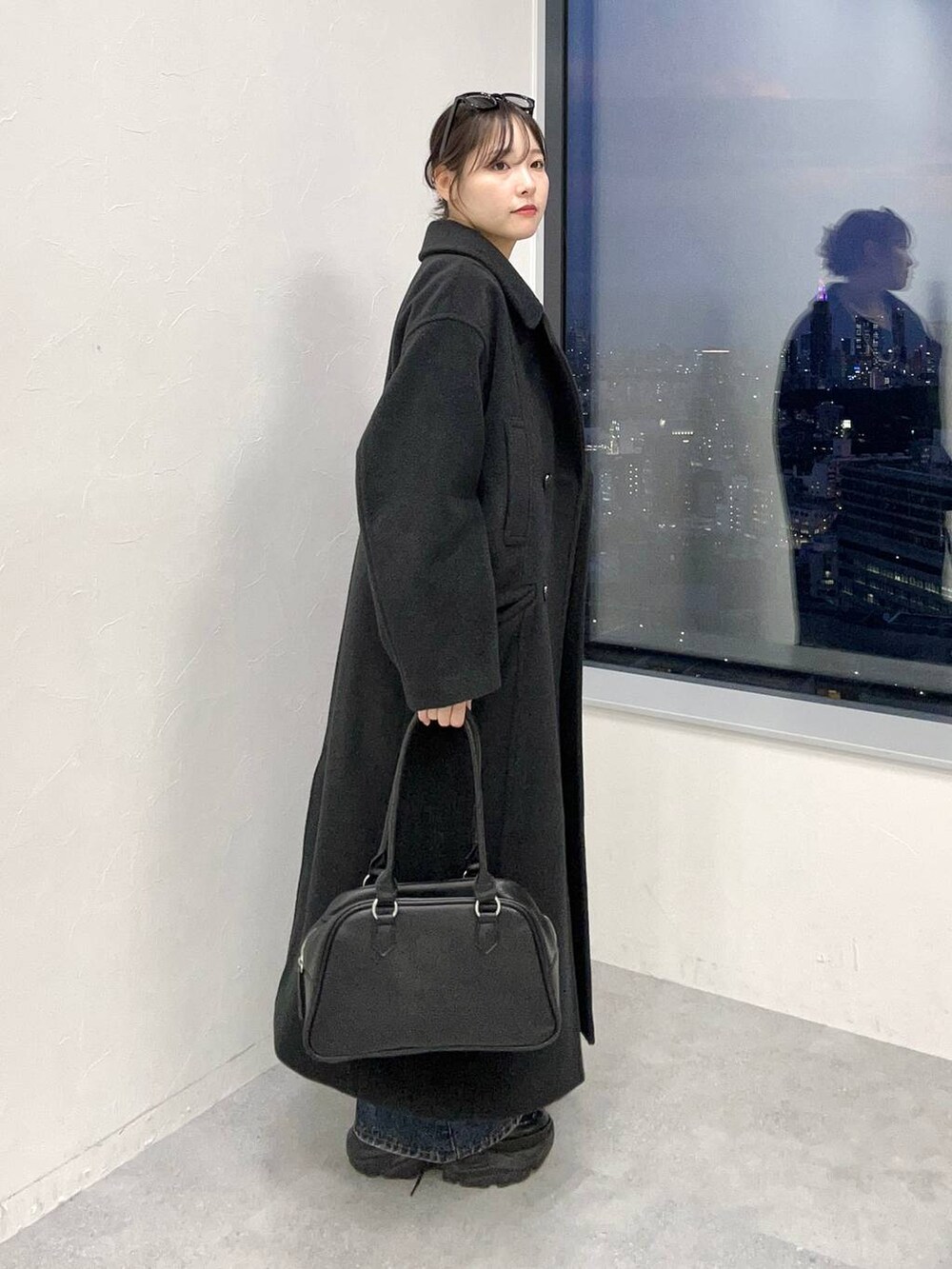 ブラック系のスニーカー、ブルー系のデニムパンツ、ブラック系のチェスターコートを着用したレディースの秋コーディネートの3枚目の写真