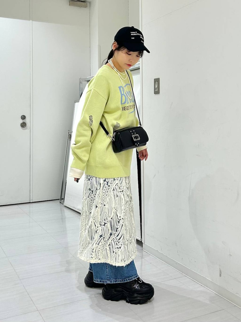 ブルー系のデニムパンツ、ホワイト系のワンピース、イエロー系のニット/セーターを着用したレディースの冬コーディネートの4枚目の写真