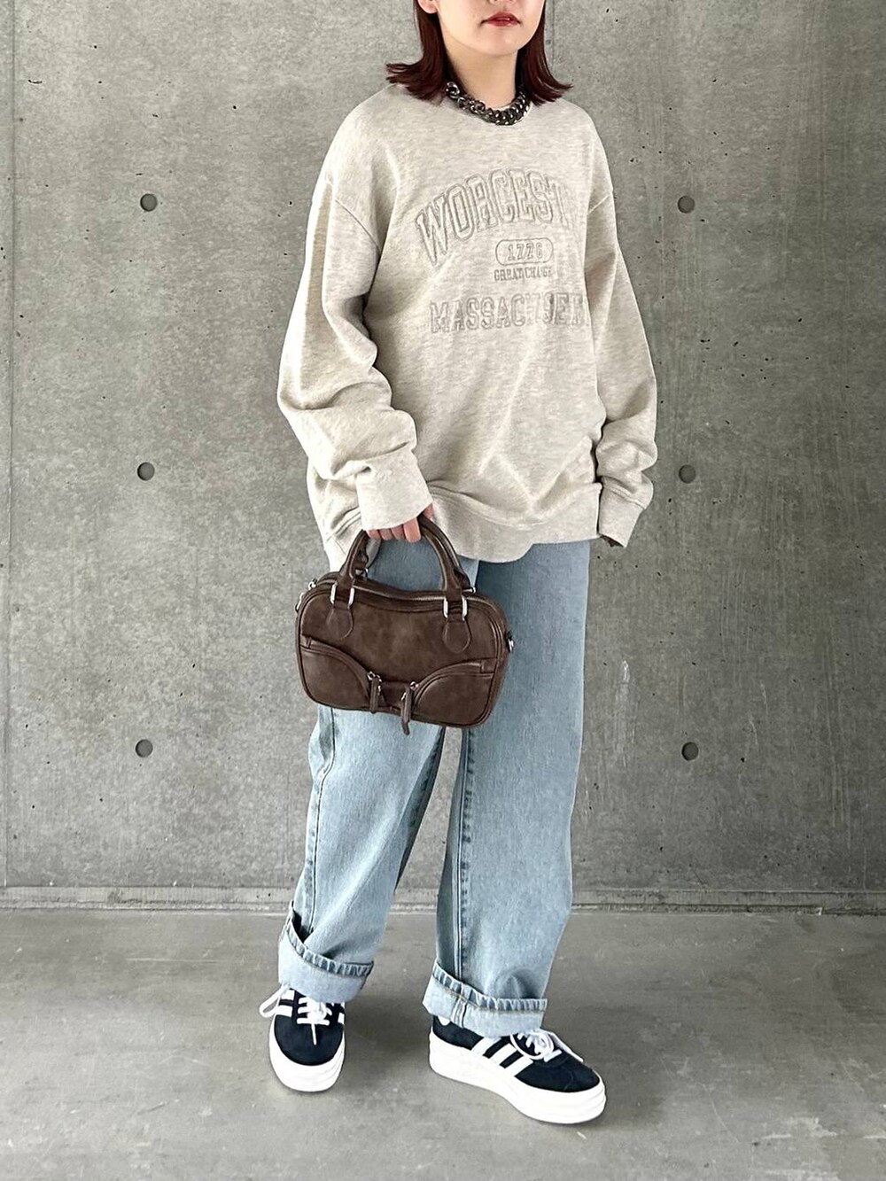 ベージュ系のスウェット、ブルー系のデニムパンツ、ブラック系のスニーカーを着用したレディースの春コーディネートの3枚目の写真