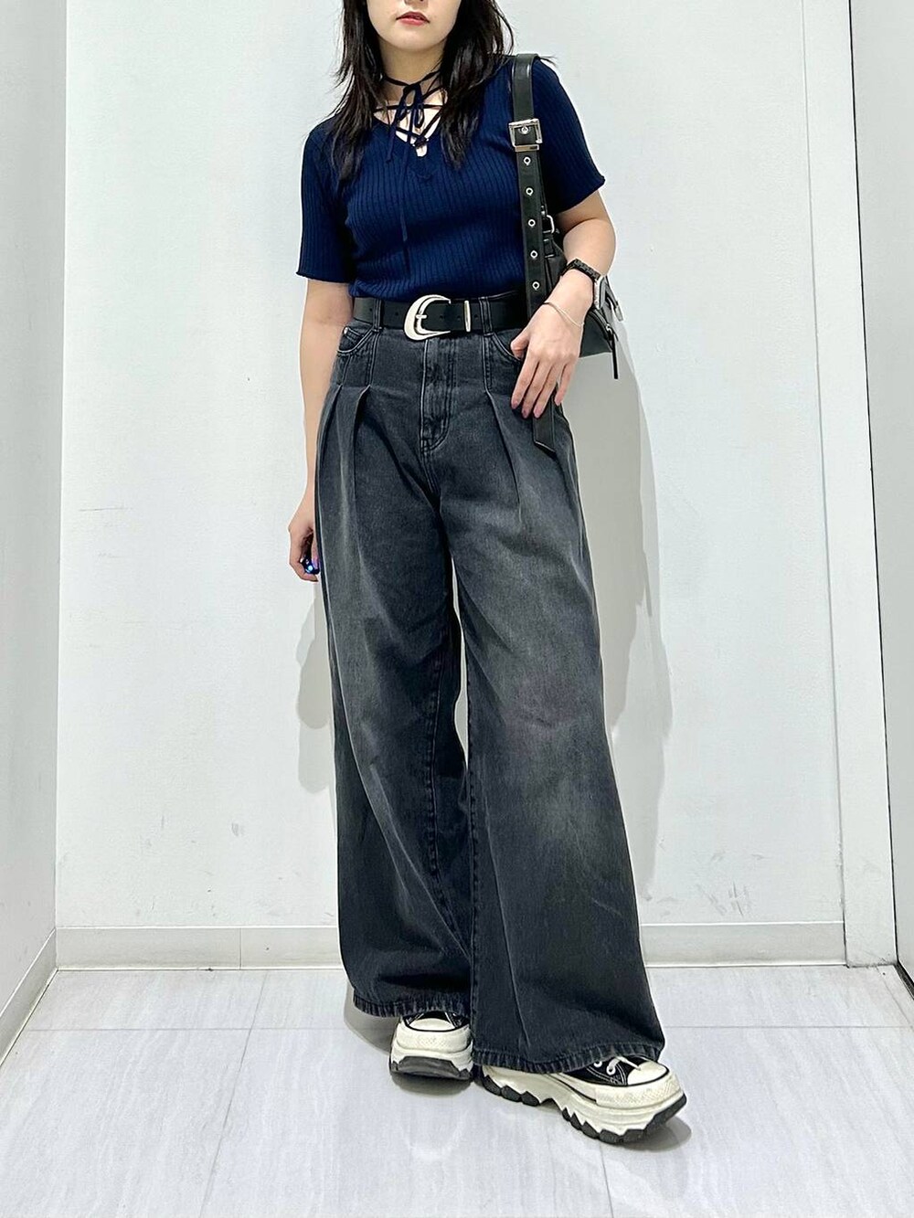 ブラック系のデニムパンツ、ブルー系のニット/セーター、ブラック系のベルトを着用したレディースの春コーディネートの4枚目の写真