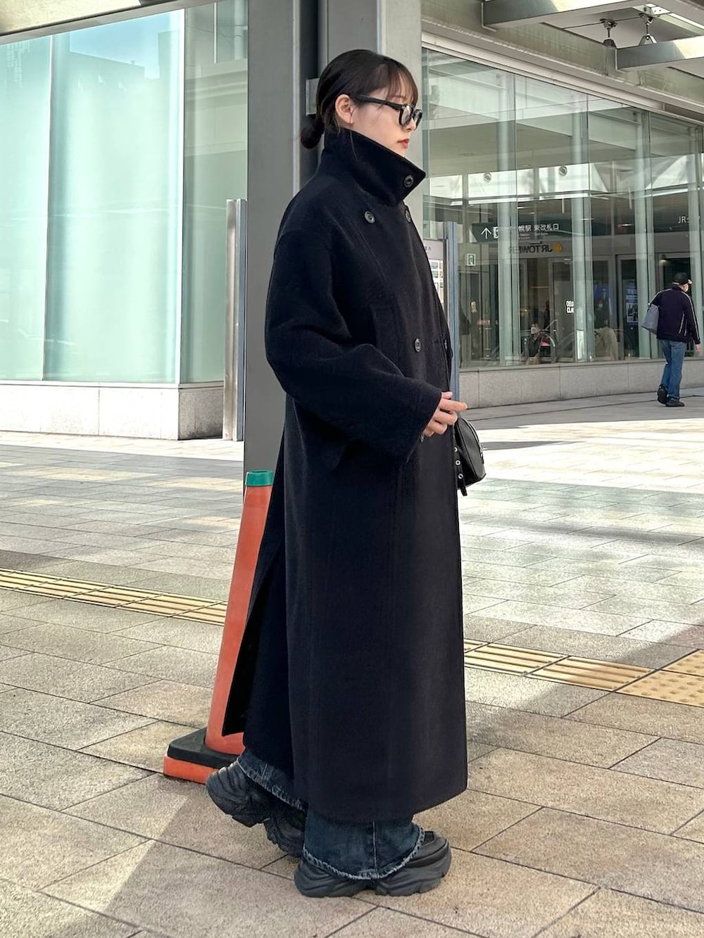 ブラック系のスニーカー、ブルー系のデニムパンツ、ブラック系のボストンバッグを着用したレディースの秋コーディネートの5枚目の写真