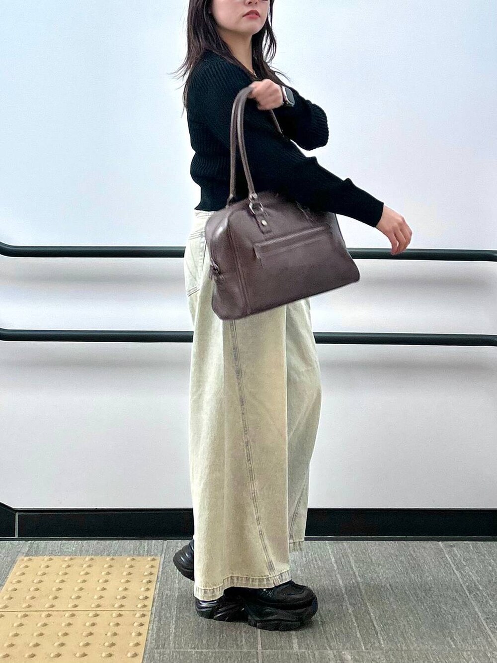 ブラック系のスニーカー、ブルー系のデニムパンツ、ブラウン系のボストンバッグを着用したレディースの夏コーディネートの5枚目の写真