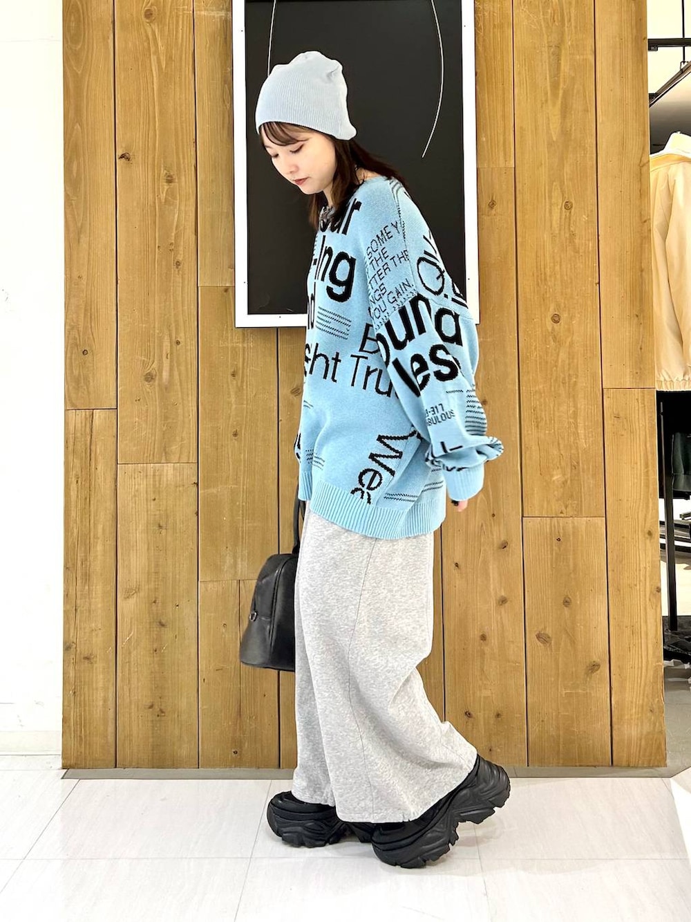 ブラック系のスニーカー、グレー系のボストンバッグ、ブルー系のニット/セーターを着用したレディースの冬コーディネートの4枚目の写真