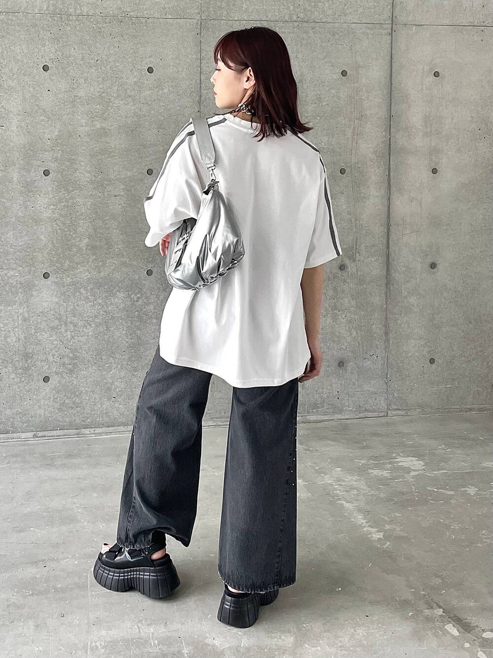 ブラック系のスニーカー、ホワイト系のTシャツ/カットソー、ブラック系のデニムパンツを着用したレディースの春コーディネートの6枚目の写真