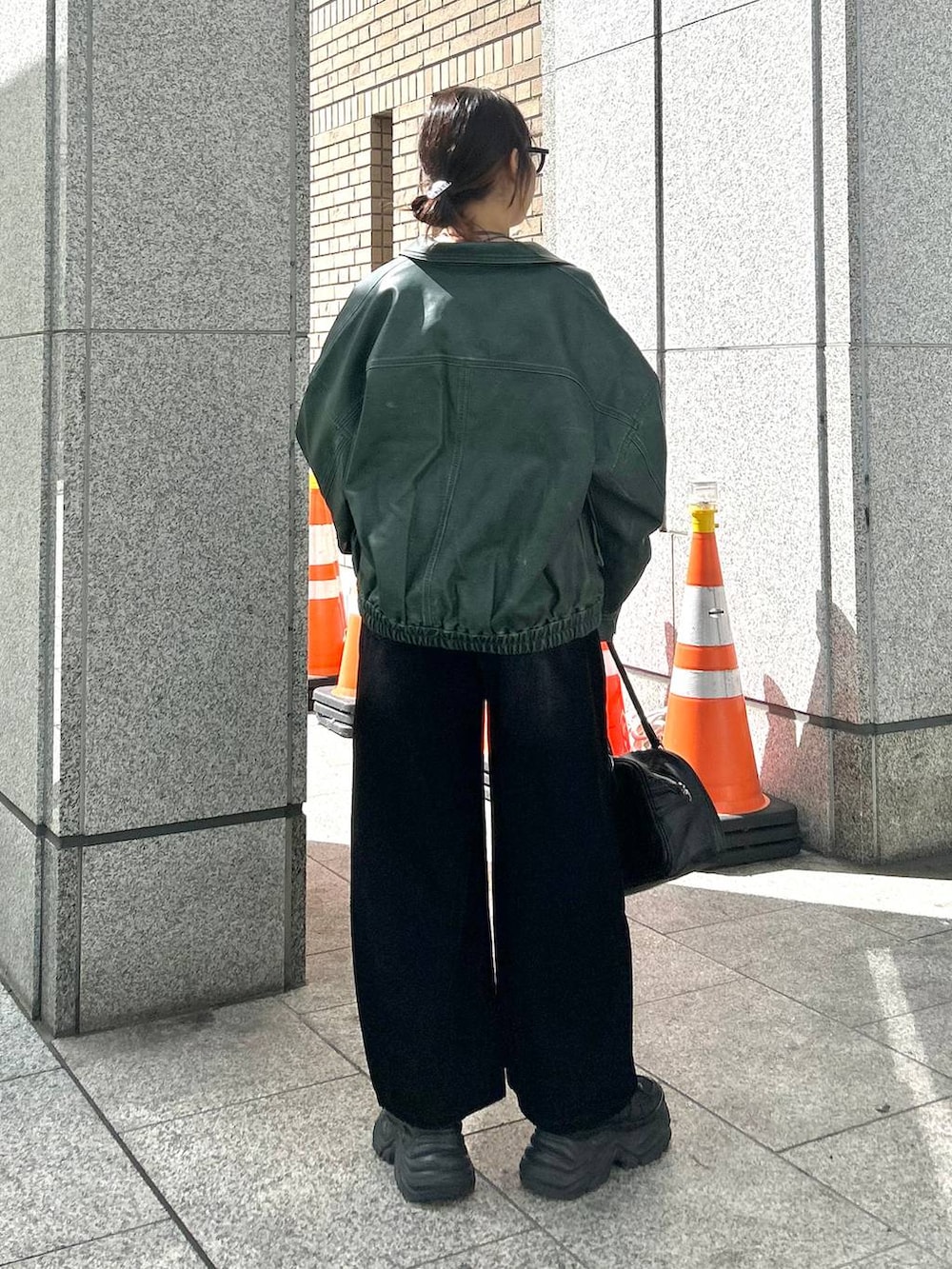 ブラック系のスニーカー、ブラック系のデニムパンツ、グリーン系のブルゾンを着用したレディースの秋コーディネートの6枚目の写真