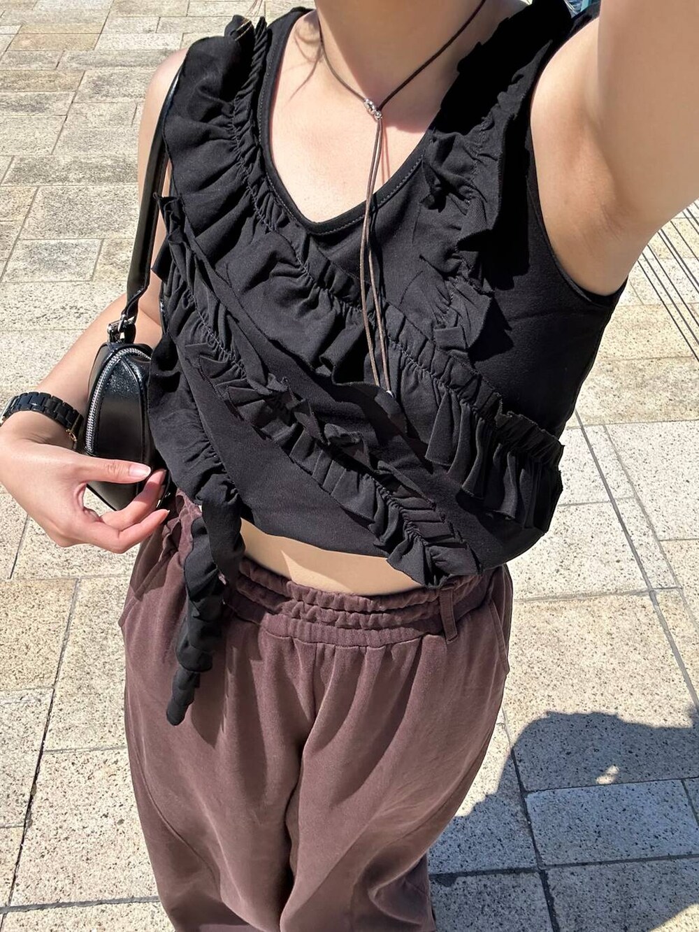 ブラック系のスニーカー、ブラック系のボストンバッグ、ブラウン系のスウェットパンツを着用したレディースの夏コーディネートの5枚目の写真