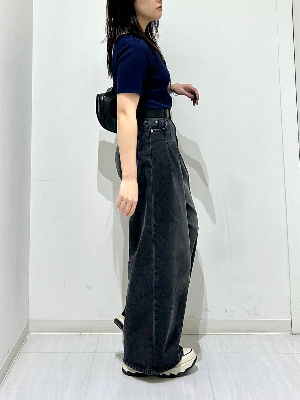 ブラック系のデニムパンツ、ブルー系のニット/セーター、ブラック系のベルトを着用したレディースの春コーディネートの6枚目の写真