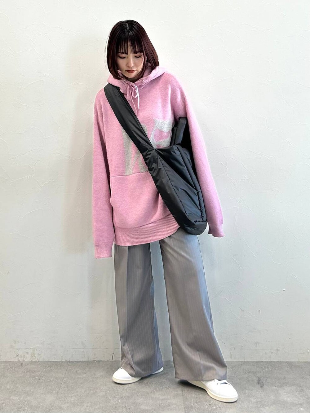 グレー系のスラックス、ブラック系のトートバッグ、ピンク系のニット/セーターを着用したレディースの冬コーディネートの3枚目の写真