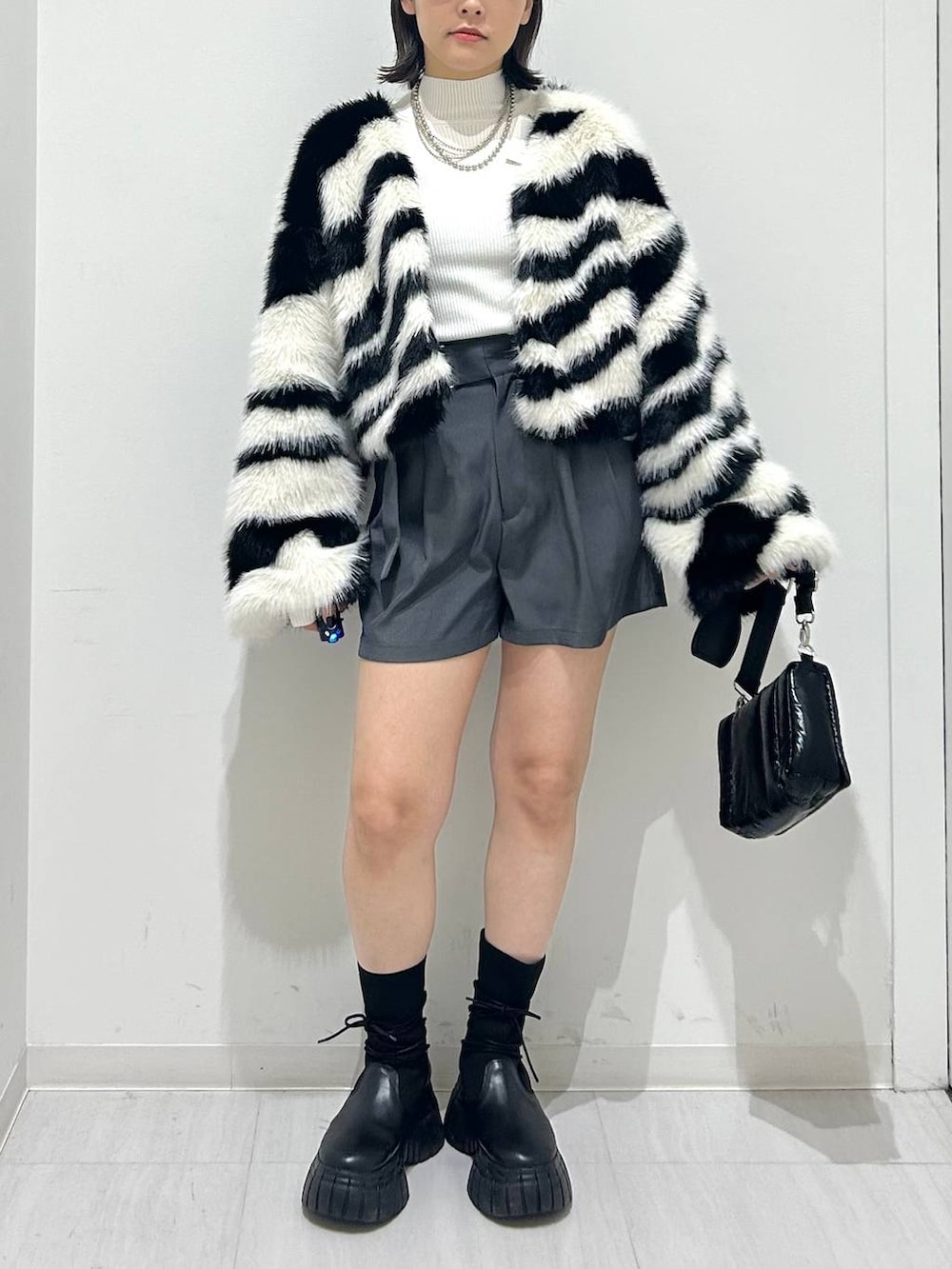 ホワイト系のニット/セーター、ブラック系のショルダーバッグ、ホワイト系のブルゾンを着用したレディースの秋コーディネートの3枚目の写真