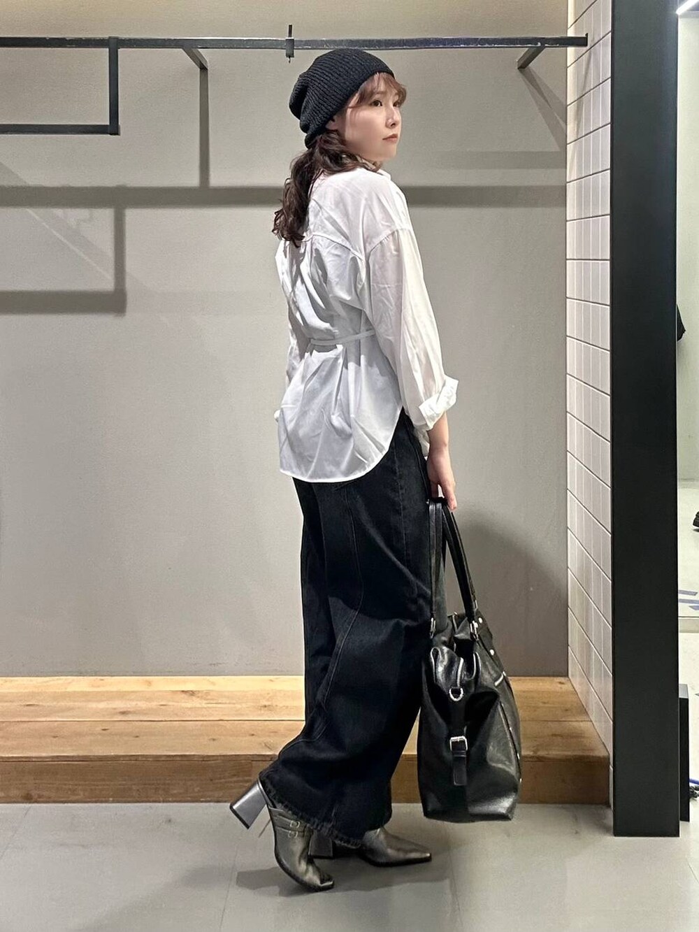 ブラック系のボストンバッグ、ブルー系のデニムパンツ、ホワイト系のシャツ/ブラウスを着用したレディースの秋コーディネートの4枚目の写真