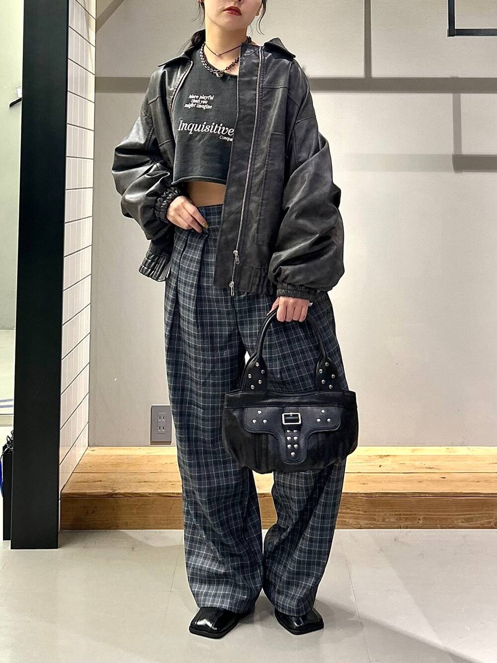 グレー系のブルゾン、ブラック系のブーツ、グレー系のスラックスを着用したレディースの秋コーディネートの2枚目の写真