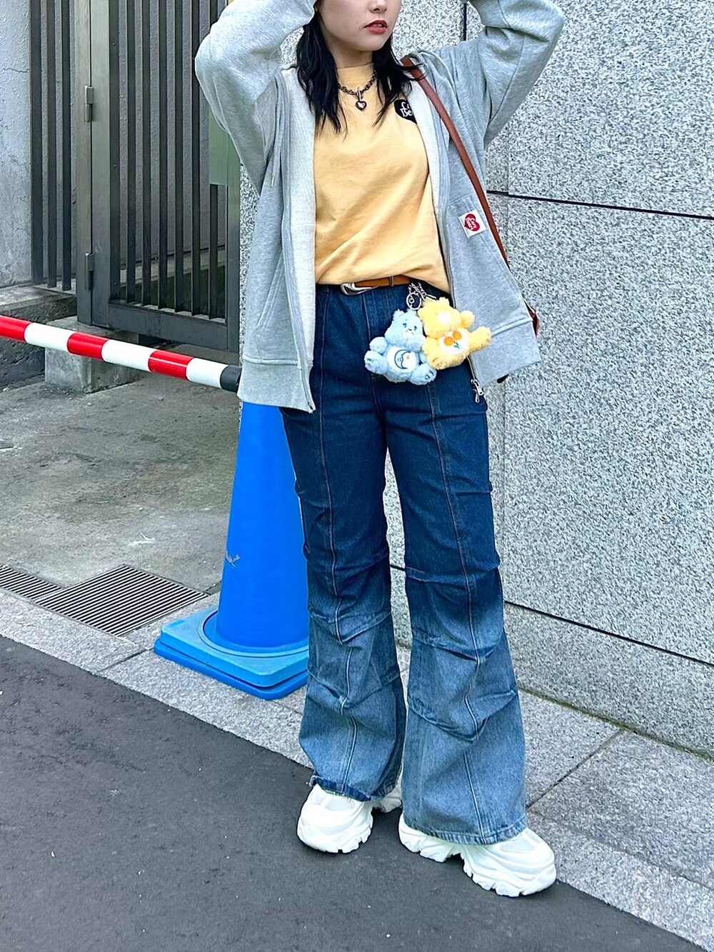 ブルー系のデニムパンツ、グレー系のパーカー、オレンジ系のTシャツ/カットソーを着用したレディースの春コーディネートの3枚目の写真